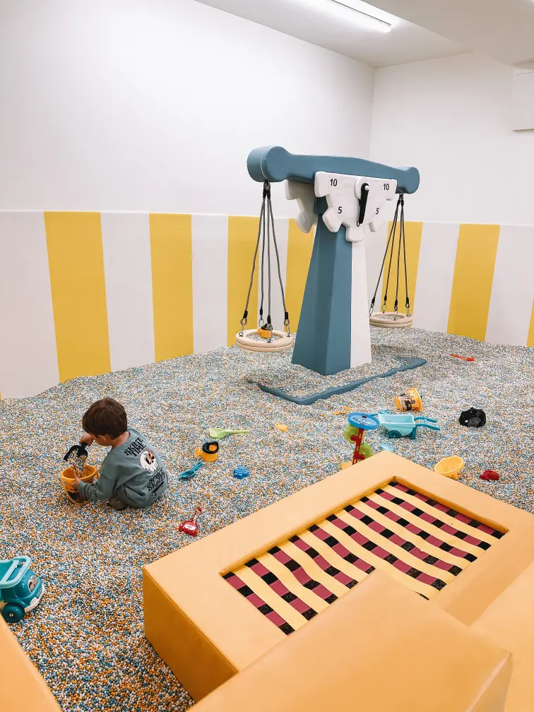 Un niño pequeño jugando en un área de juegos, disfrutando de un ambiente divertido y seguro.
