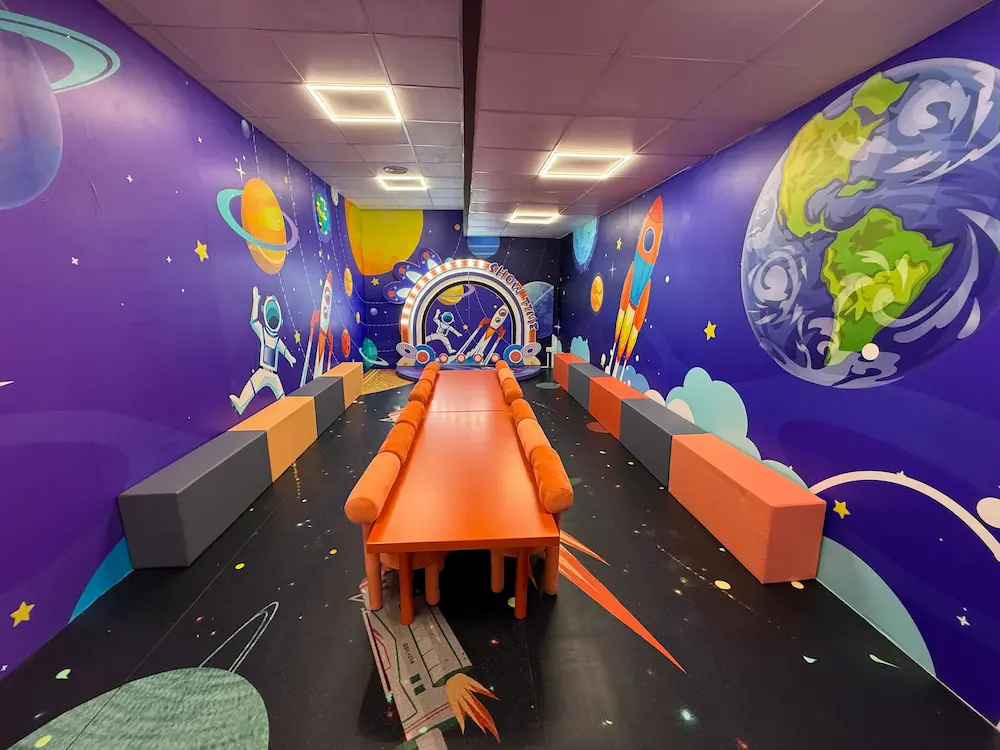 Sala infantil temática del espacio con planetas, astronautas y cohetes.